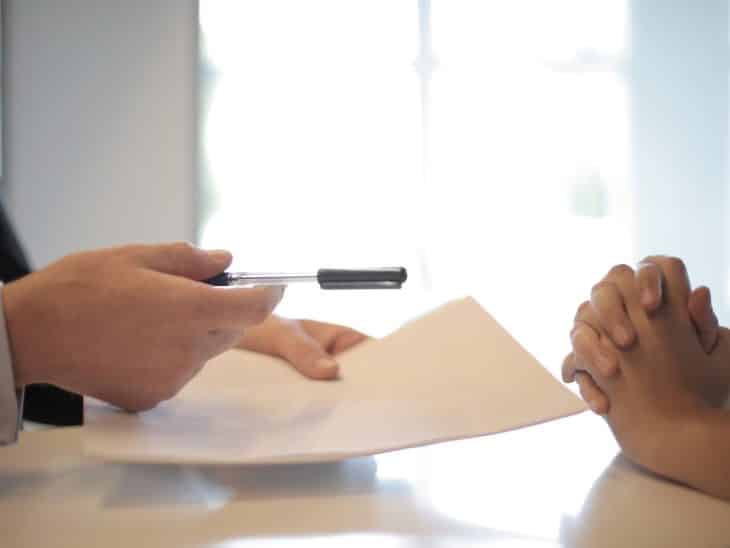 Crop businessman giving contract to woman to sign